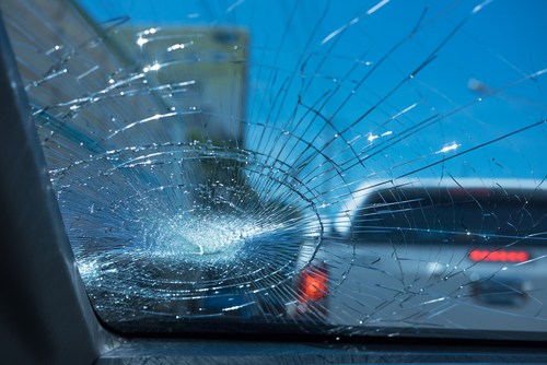 A cracked windshield of a car in traffic