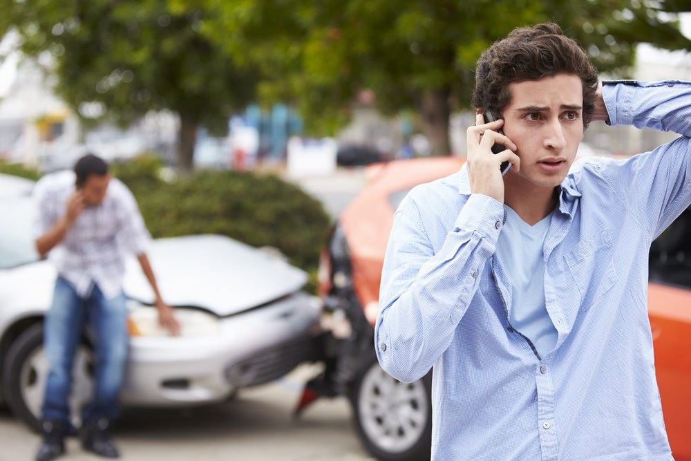 A young man making a call after an accident.