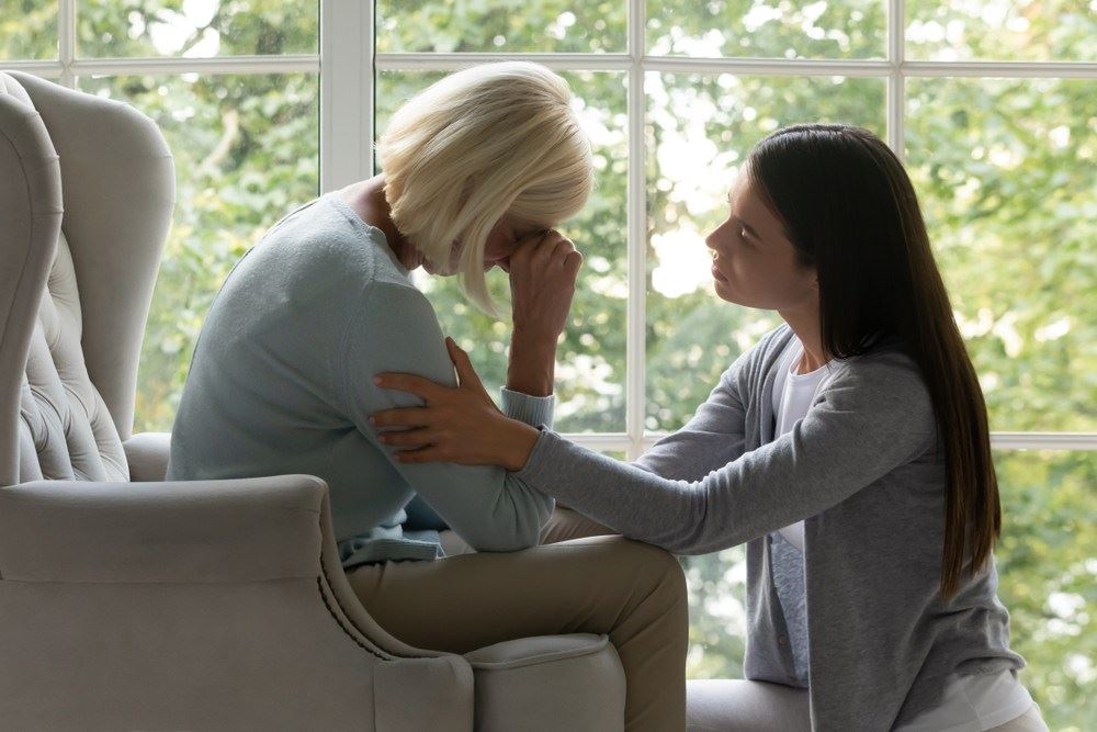 younger woman calms grieving older woman