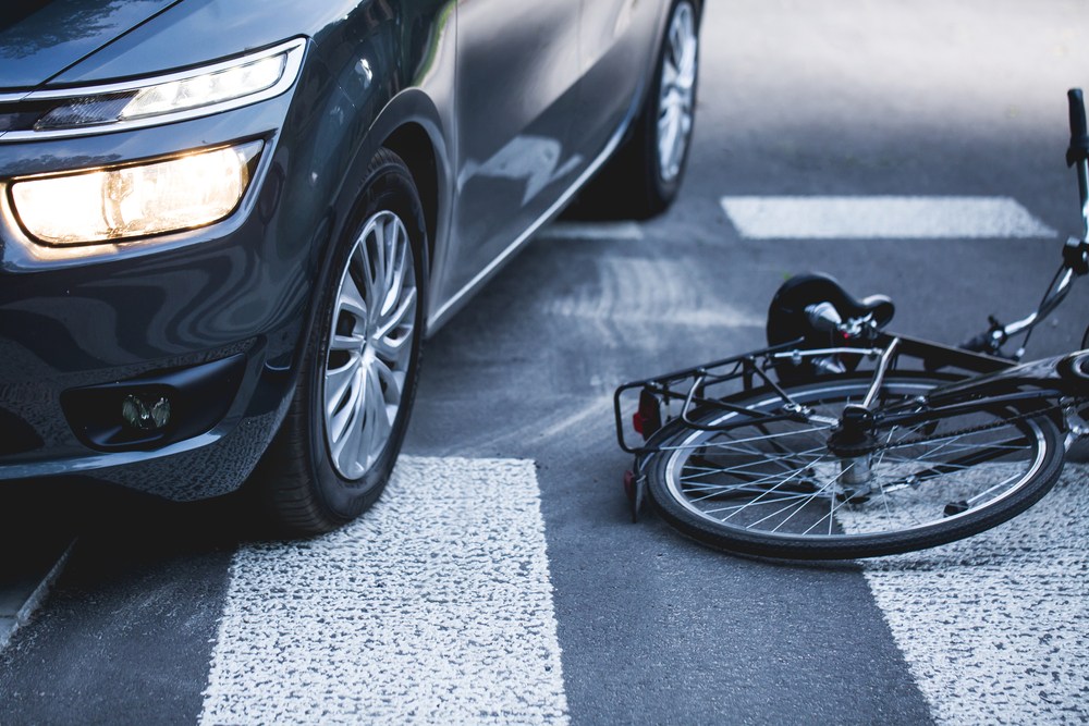bicycle lying in crosswalk next to vehicle after collision