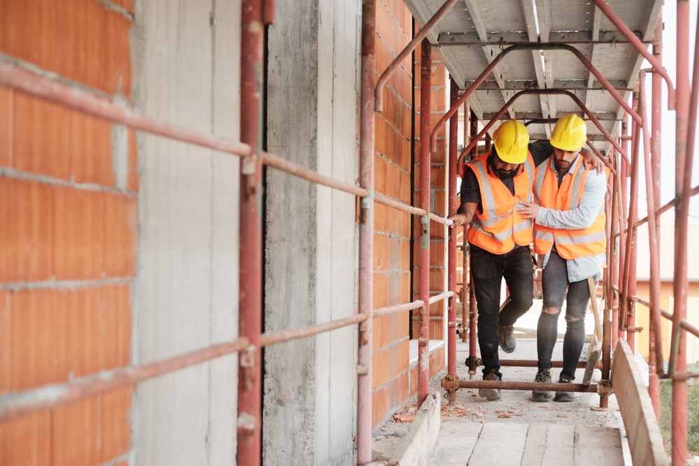 construction worker helping injured coworker walk