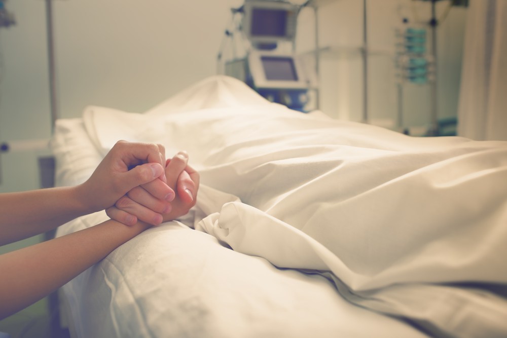 woman mourns deceased husband in hospital bed