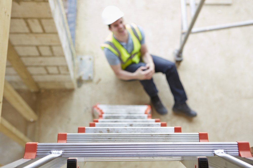 construction worker holding his knee after a fall off a ladder