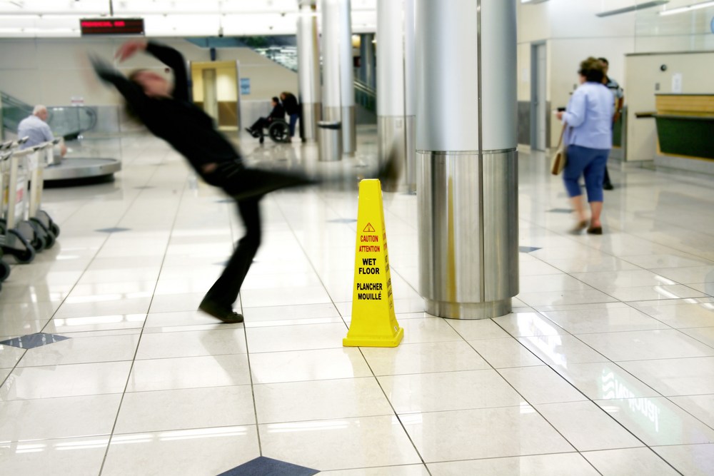man slipping next to a wet floor sign