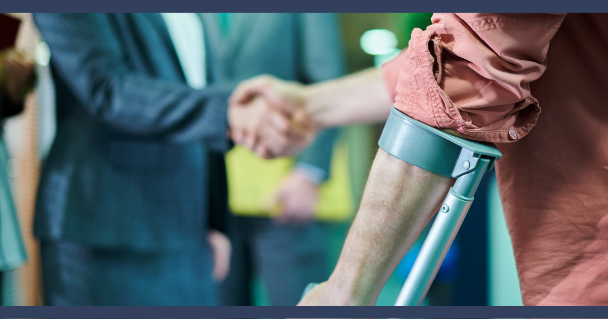 Man in suit shaking hands with injured man who is leaning on a crutch