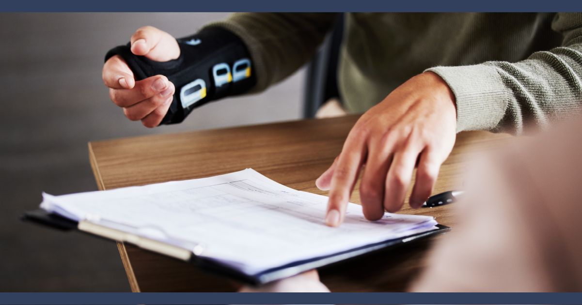 man with arm in medical cast looking at paperwork