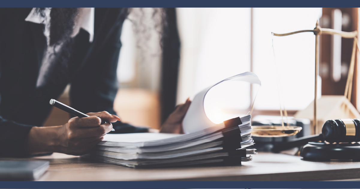 Close up of the desk of a lawyer with person reviewing a stack of paperwork