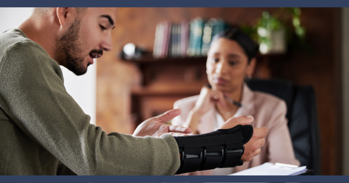 Man with arm in a brace signing a legal document in a lawyer office