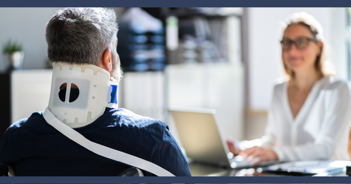 view from behind of a seated man who has a neck brace on, he is looked at a woman who is typing on a keyboard.