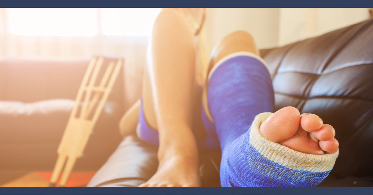 close up of a person on a sofa, with their leg in a blue medical support cast.