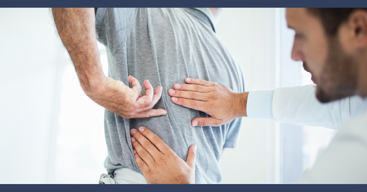 man undergoing examination of this back ache, doctor is pressing on his spine