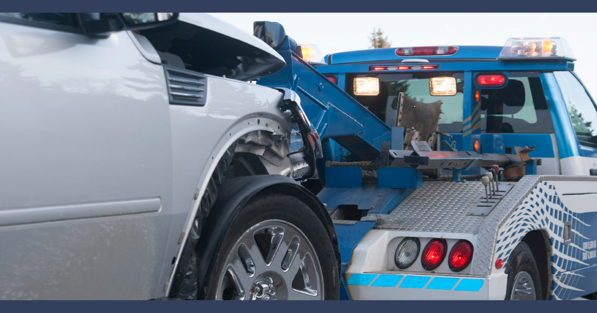 wrecked car being towed away by a blue tow truck