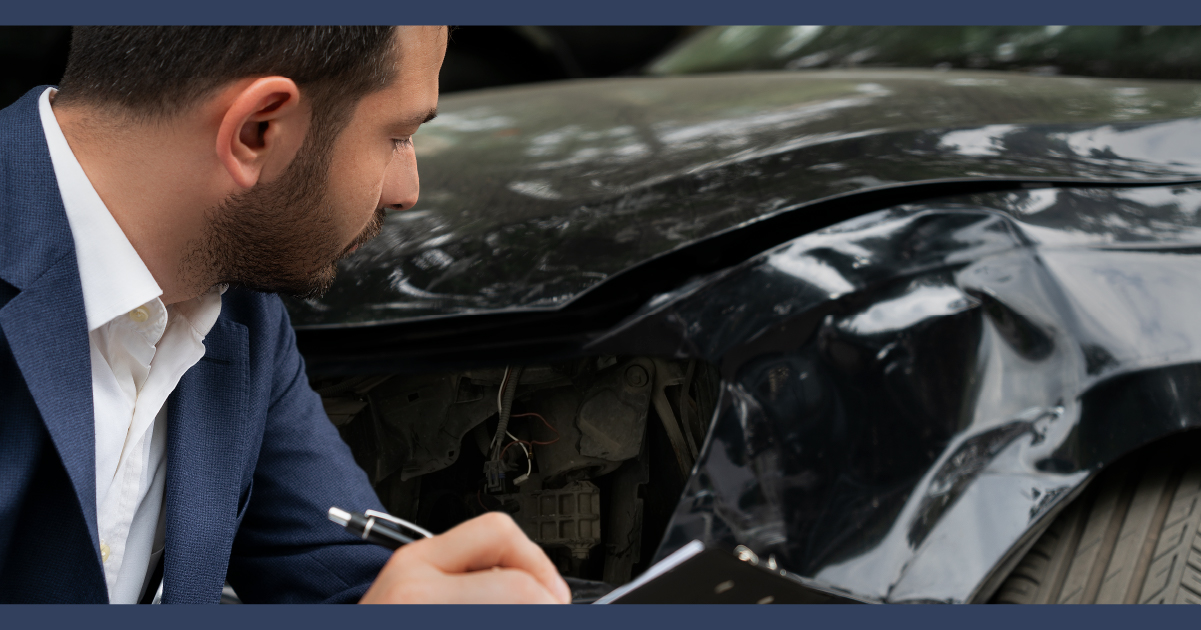 close up of a man in a suit inspecting a damaged car and making notes