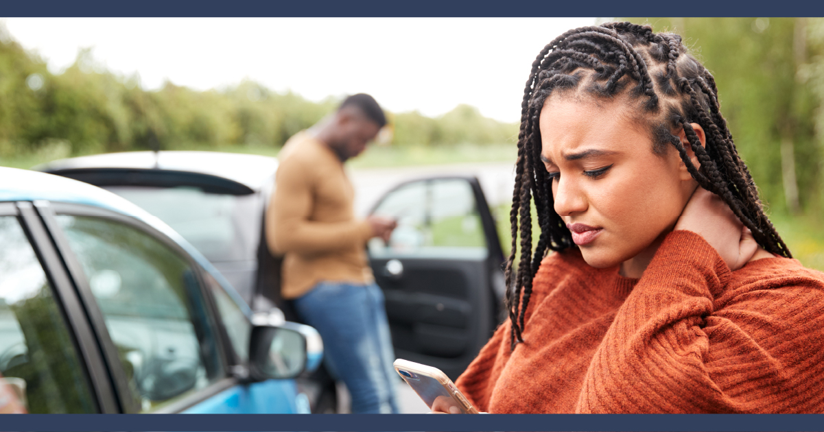 Lady holding neck after a car accident, other car and driver standing in background