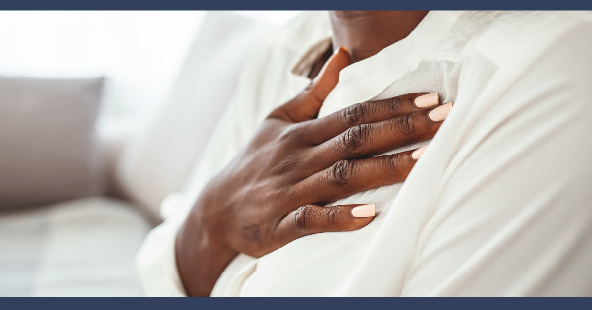 Dark skinned lasy wearing white with her hand on her heart. close up on chest area and hand