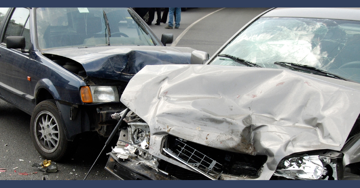 Close up view of a silver car having been hit by a blackcar in the side, both cars have crumple damage form the accident