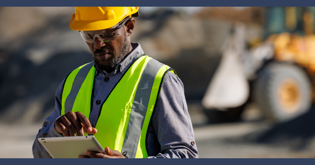 dark skinned construction working wearing hi-vis jacket and hard on construction site looked at paperwork