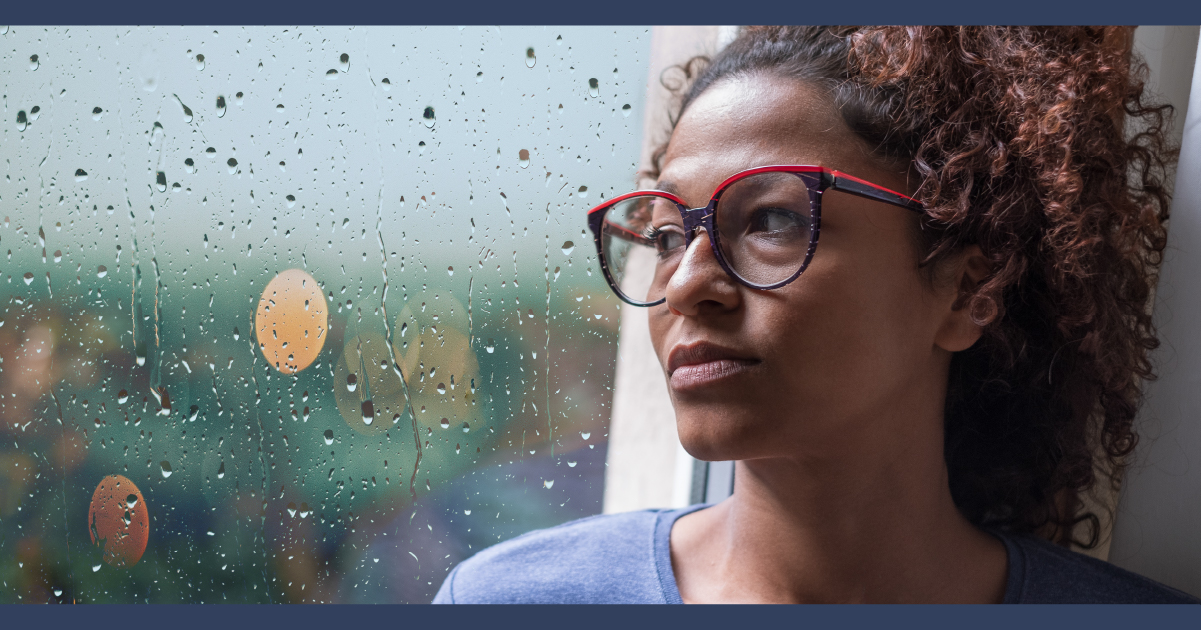 Sad woman looking out rainy window