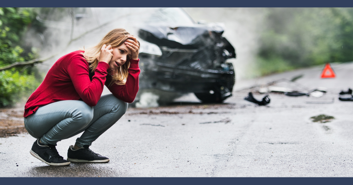Woman on mobile phone with a blue crashed car in the background