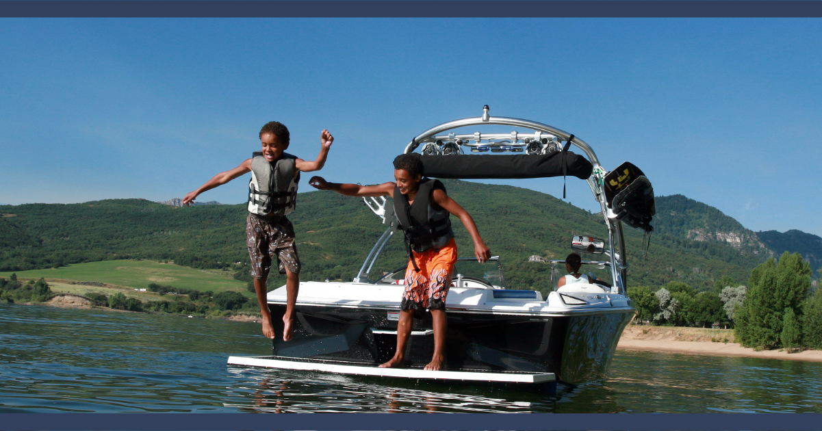 Two people jumping off the back of a boat into clear water.