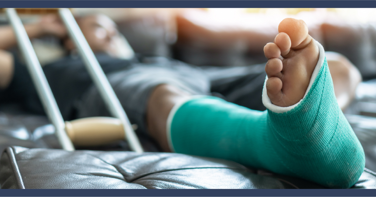 clsoe up of a leg in a plaster cast with a crutch nearby