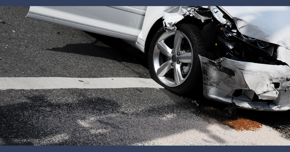 Close up view of a silver car with damage to the front fender and front wheel