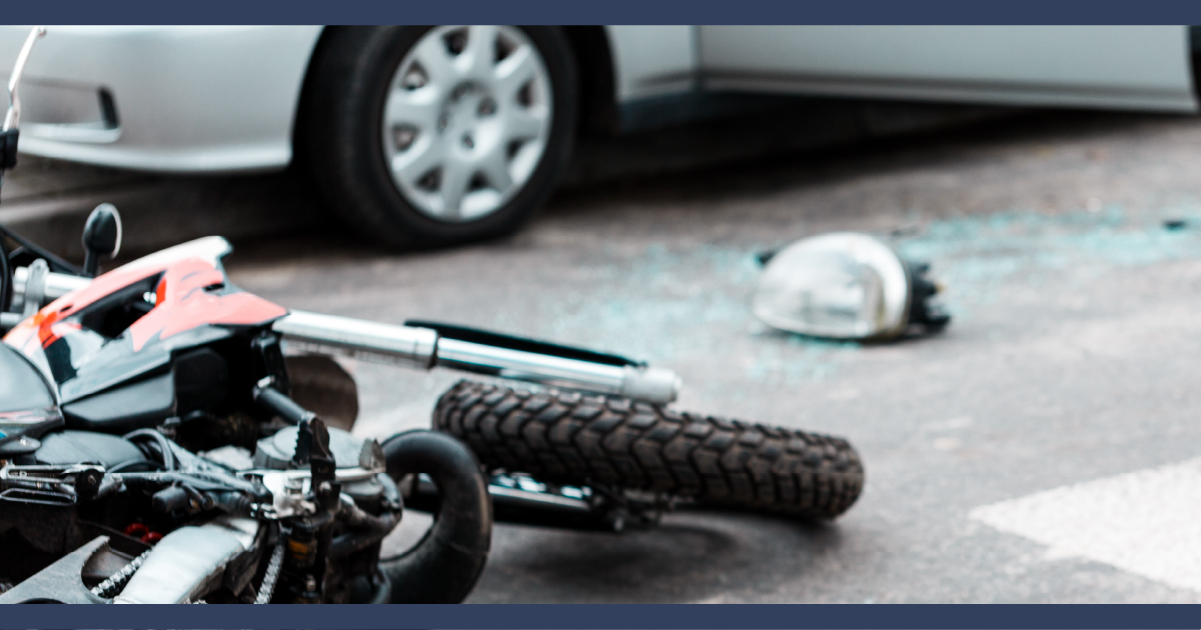 Motorcycle on its side next to a car after a crash