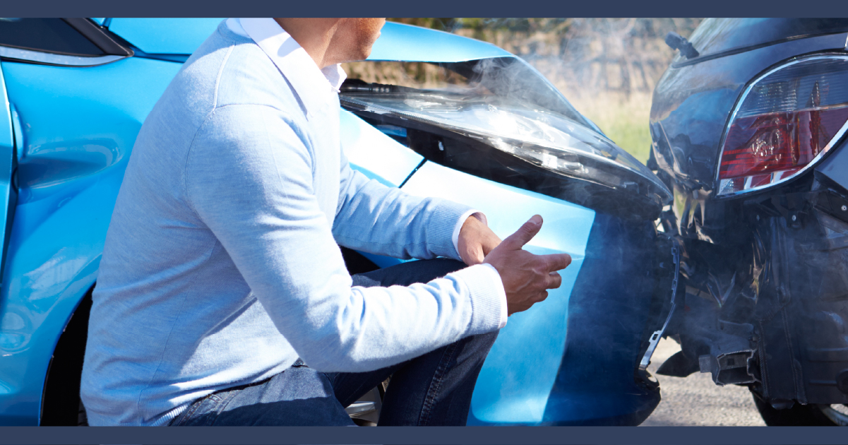 Man standing infront of two crashed cars.