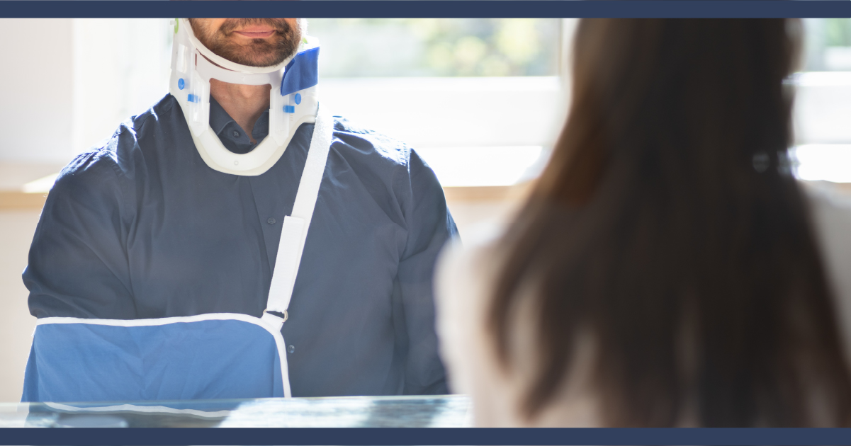 Man with neck brace and arm in a sling sitting down in a meeting with a woman