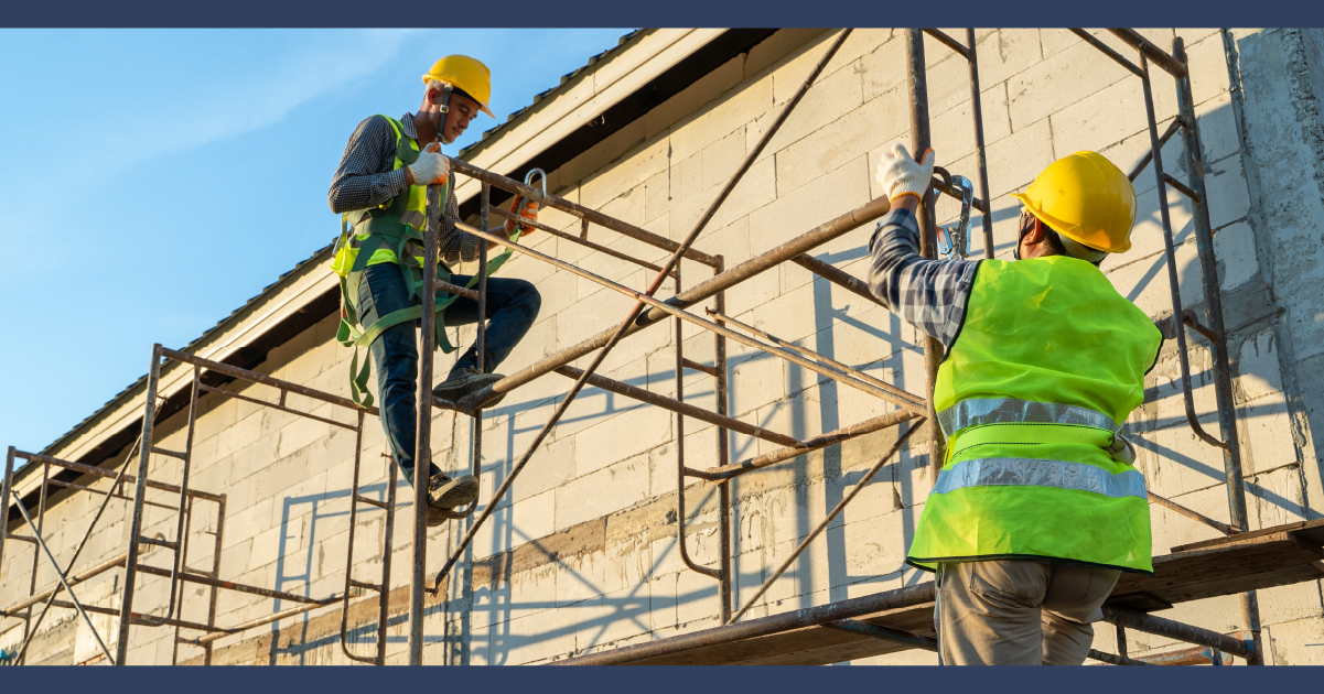 Two construction workers on scaffold.