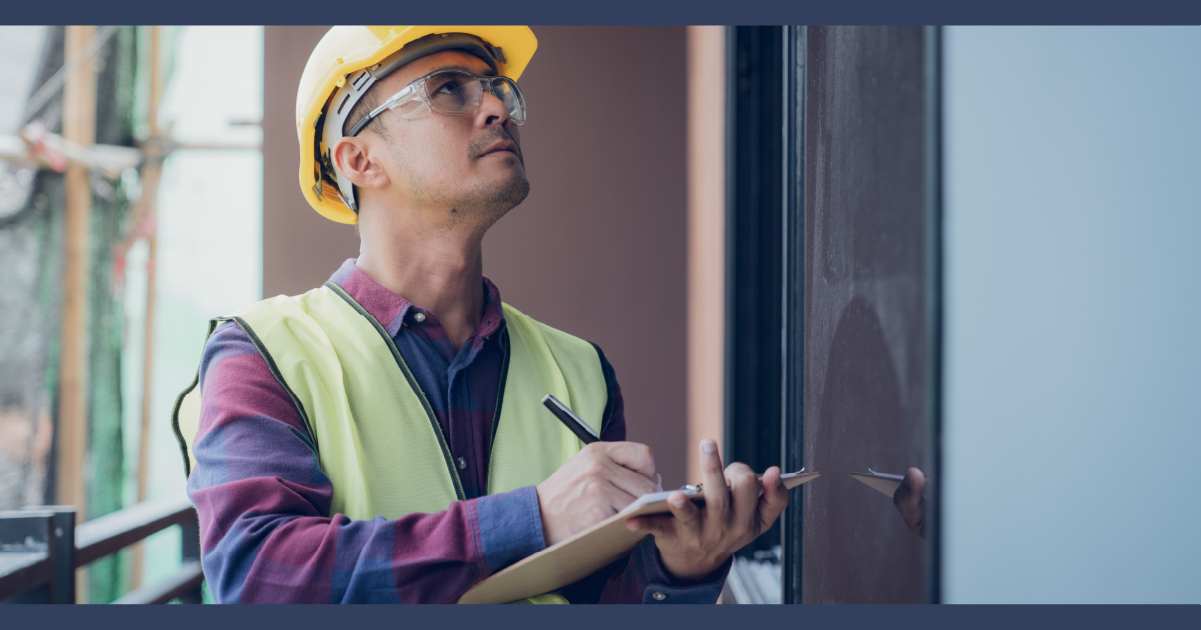 Man in hardhat with clipboard on work site
