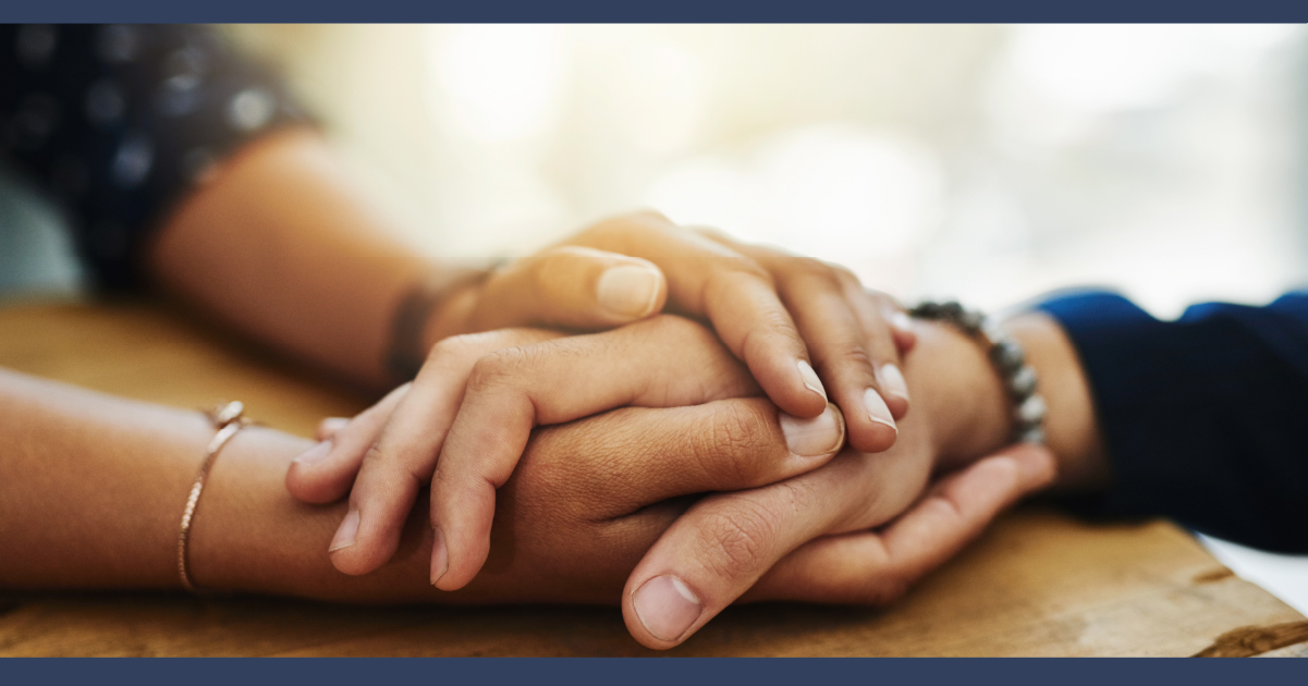 Two people holding hands in an act of comfort.