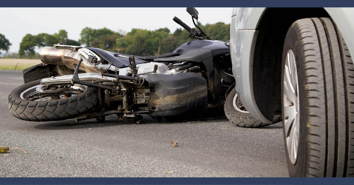 Motorcycle wreckage under front of a car