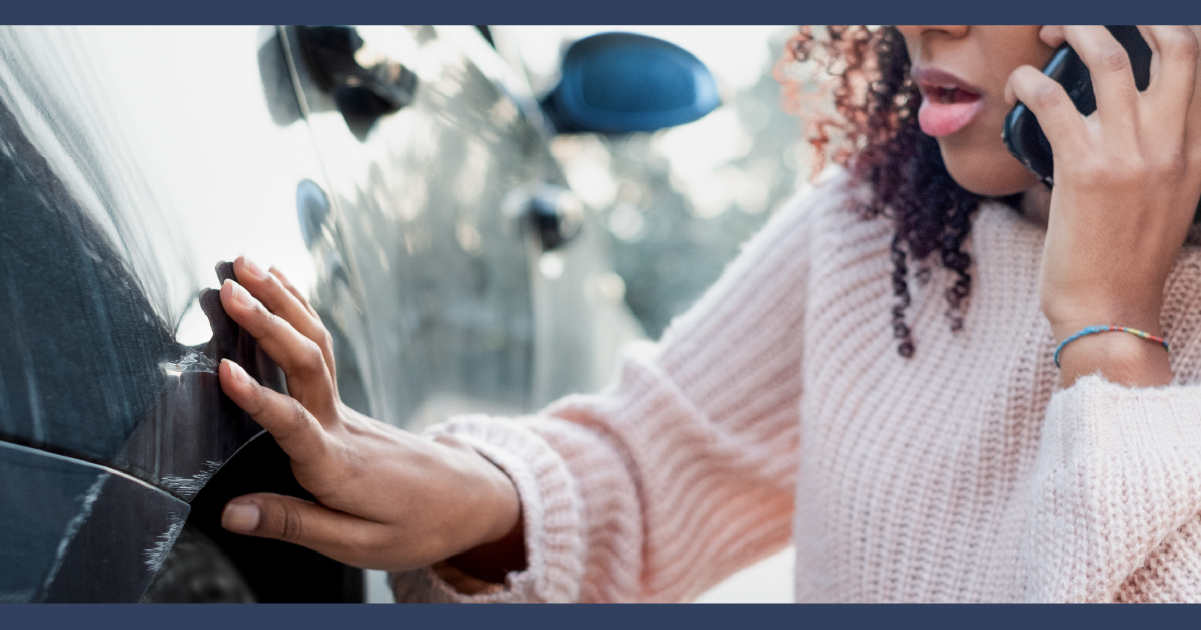 Lady checking car damage after accident.