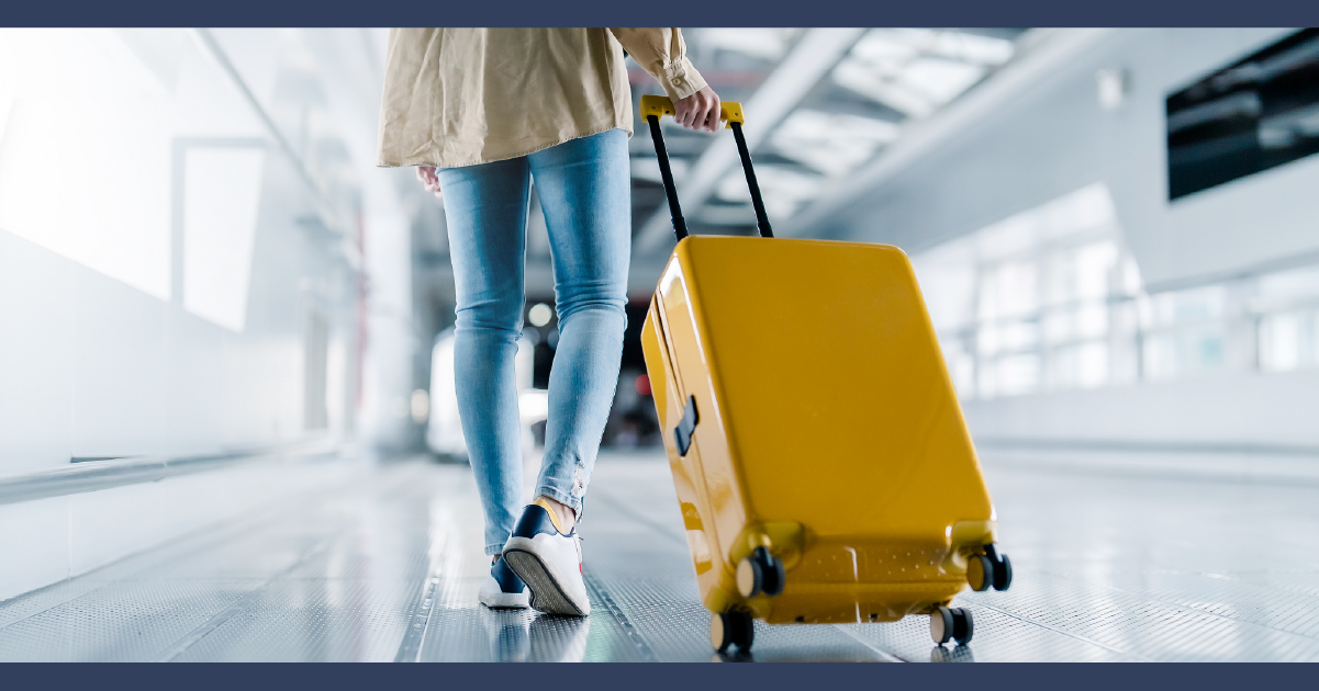 Woman pulling yellow suitcase through airport hallway
